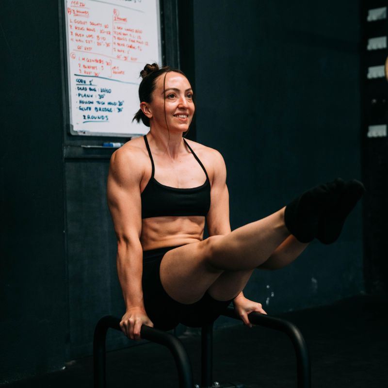 Abbey Willis holding an L sit on parallettes